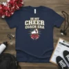 Navy t-shirt with "In My Cheer Coach Era" text, megaphone, and red cheerleading pom-poms graphic