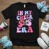 Retro 'In My Cheer S Era' graphic tee with two cartoon cheerleaders holding pom-poms