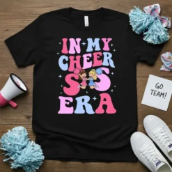 Retro 'In My Cheer S Era' graphic tee with two cartoon cheerleaders holding pom-poms