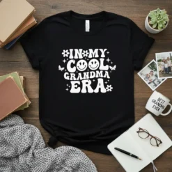 Retro "In My Cool Grandma Era" text design with smiley face and butterflies on a black t-shirt