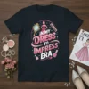 In My Dress To Impress Era text with graphics of a mirror, comb, and nail polish on a dark t-shirt