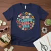 In My Flower Girl Era text surrounded by a circle of colorful retro flowers on a navy blue t-shirt