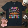 In My Monster Truck Mama Era t-shirt design with three colorful monster trucks and retro groovy text