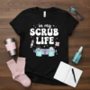 Black t-shirt with "in my SCRUB LIFE" text and medical graphics like a syringe and stethoscope