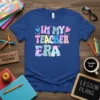 In My Teacher Era text in colorful retro groovy font with hearts and butterflies on a blue t-shirt