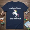 White unicorn with rainbow mane and tail, text "In a field of horses Be a UNICORN" on navy t-shirt