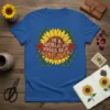 In A World Of Roses Be A Sunflower quote t-shirt with a bold sunflower graphic and red roses, presented on