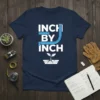 Inch By Inch quote with measuring tape and seedling graphic on navy t-shirt