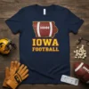 Navy blue t-shirt featuring the text "IOWA FOOTBALL" with a football graphic shaped like the state of Iowa