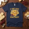 It Ain't Easy Being Cheesy quote on a navy t-shirt with a muscular cheese character graphic