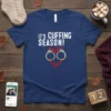White text "IT'S CUFFING SEASON!" above a heart made of red chain and handcuffs on a navy blue t-shirt
