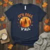 It's Fall Y'All text with a circular forest graphic featuring autumn trees and falling leaves, on a navy blue t-shirt