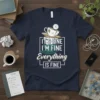 IT'S FINE I'M FINE Everything IS FINE quote on a dark navy t-shirt with a cracked teacup graphic