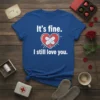 Blue t-shirt with white text "It's fine. I still love you." and a cracked heart graphic bandaged with adhesive strips