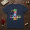 Navy blue t-shirt with "it's MAHJONG time" text and colorful mahjong tile graphics, including bamboo, plum blossom, and yin yang