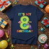 Navy t-shirt with "IT'S MY 8TH BIRTHDAY" text and cute cartoon monsters around a large green number 8