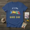 It's My Bird Day t-shirt design with cute cartoon birds wearing party hats on a branch, confetti, and musical notes