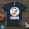 Navy blue t-shirt with "IT'S MY BIRTHDAY SIGN MY SHIRT" text and festive graphics including balloons and gifts