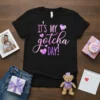 Black t-shirt with "It's MY Gotcha DAY!" text in pink and purple gradient, adorned with hearts