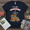 Navy t-shirt with white and red text "IT'S NOT HOARDING IF I LOVE IT" above a wooden chest filled with