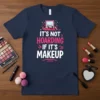 T-shirt with the text "IT'S NOT HOARDING IF IT'S MAKEUP" in pink and white, featuring makeup vanity graphics