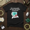 Black t-shirt with white text "It's now safe to turn off your computer" and a graphic of a retro computer