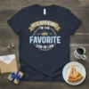 T-shirt design with text "IT'S OFFICIAL I'M THE FAVORITE SON-IN-LAW" in a circular emblem with a crown graphic
