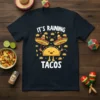 It's Raining Tacos graphic t-shirt design featuring a happy taco character holding sombreros and surrounded by falling tacos