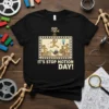 Black t-shirt with "IT'S STOP MOTION DAY!" text and a film frame graphic showing characters running and a lightbulb