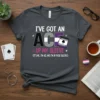 A dark grey t-shirt with the text "I've Got An Ace Up My Sleeve" in white, purple, and grey, featuring