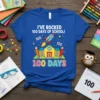 Blue t-shirt with "I've Rocked 100 Days of School" text, a rocket, schoolhouse, and pencils graphic