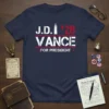 Navy blue t-shirt with "J.D. Vance '28 For President" text in white and red, featuring a bullet graphic and distressed