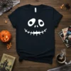 Black t-shirt featuring a white, stylized Jack O Lantern face with large circular eyes and a jagged stitched smile