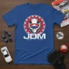 JDM Made In Japan T-Shirt with a white helmet graphic and red and blue sunburst pattern. Bold white "JDM" text