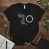 Black t-shirt with white text "Jesus" next to a crown and a crown of thorns graphic, symbolizing faith