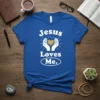 Blue t-shirt with white text "Jesus Loves Me" and graphic of hands holding a heart