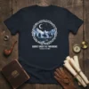 Navy t-shirt graphic: JOURNEY UNDER THE TWIN MOONS Guardians of the Night depicts riders under twin moons
