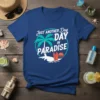 Just Another Day IN PARADISE text with palm trees, surfboards, and ocean waves graphic on a blue t-shirt