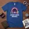 Blue t-shirt featuring a stylized cave entrance with purple and pink crystals, and the text "JUST ONE MORE."