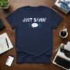 Navy t-shirt with white text "JUST SAYIN'" above a blue speech bubble graphic, representing witty sayings