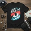 Black t-shirt with bold white and blue text "JUST SEND IT!" and a silhouette of a snowboarder mid-air over mountains