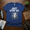 Blue t-shirt with white text "JUST STOP OIL" and graphic of a fist breaking oil pipes