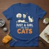 Just A Girl Who Loves Cats text with illustrations of cats in various poses on a royal blue t-shirt