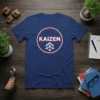Blue t-shirt featuring the word KAIZEN in white text with a red circle border and grey upward arrows graphic