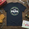 Keep Calm and Papa Will Fix It text design on a navy blue t-shirt with tools graphic