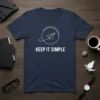 Keep It Simple quote with a minimalist paper airplane graphic inside a circle on a navy blue t-shirt