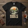 Black t-shirt with "Keep It Simple" text and a circular nature graphic featuring stacked stones, river, and sunset