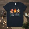 Kindness makes life a little warmer quote with campfire and hot cocoa graphic on a navy t-shirt