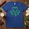 Green "Kiss Me I'm Irish" text inside a decorative shamrock graphic on a royal blue t-shirt