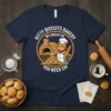 Kitty Biscuits Bakery We Knead Em You Need Em t-shirt with a cartoon cat baker in front of a brick